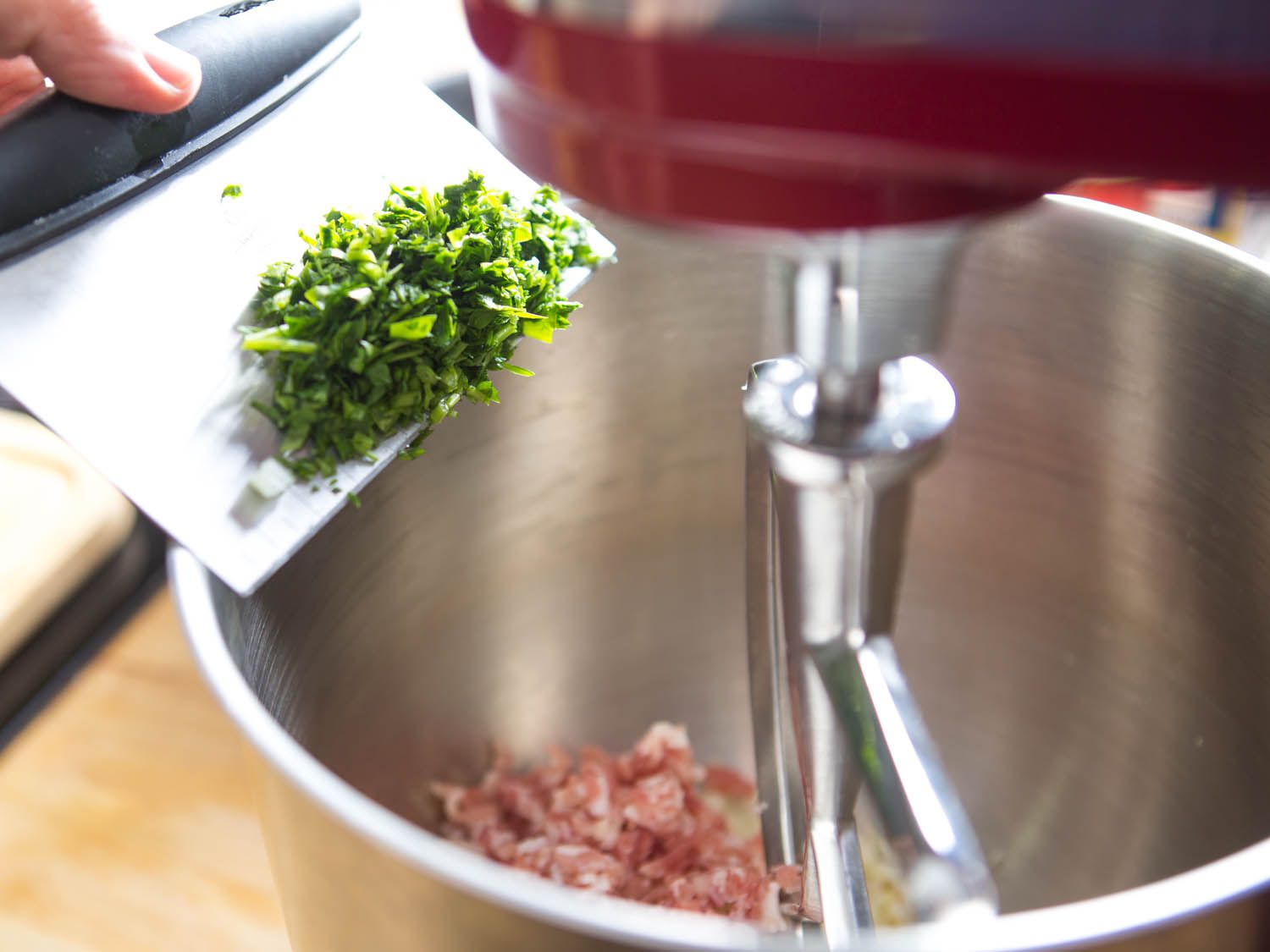 Adding chopped parsley to bowl of stand mixer for meatballs.