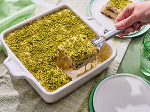 A square dessert dish of pistachio tiramisu with a portion being served
