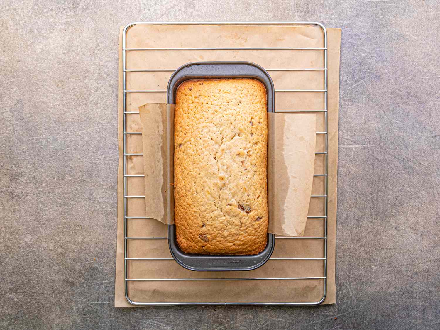A loaf cake in a baking tin on a cooling rack