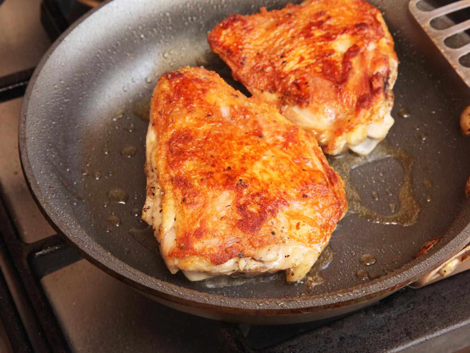 Two chicken thighs browning in a skillet after being cooked sous vide. 