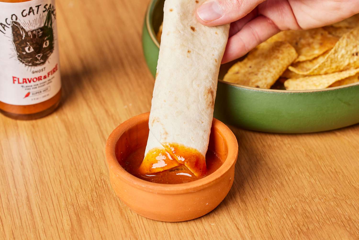 Person dipping tortilla into Flavor and Fire Foods Taco Cat Sauce