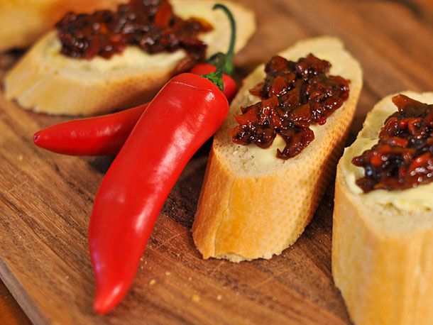 Hot chile chutney, served on slices of baguette. Two hot red chiles are nestled between the slices.