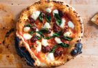 Charred pizza with 'nduja on wooden surface