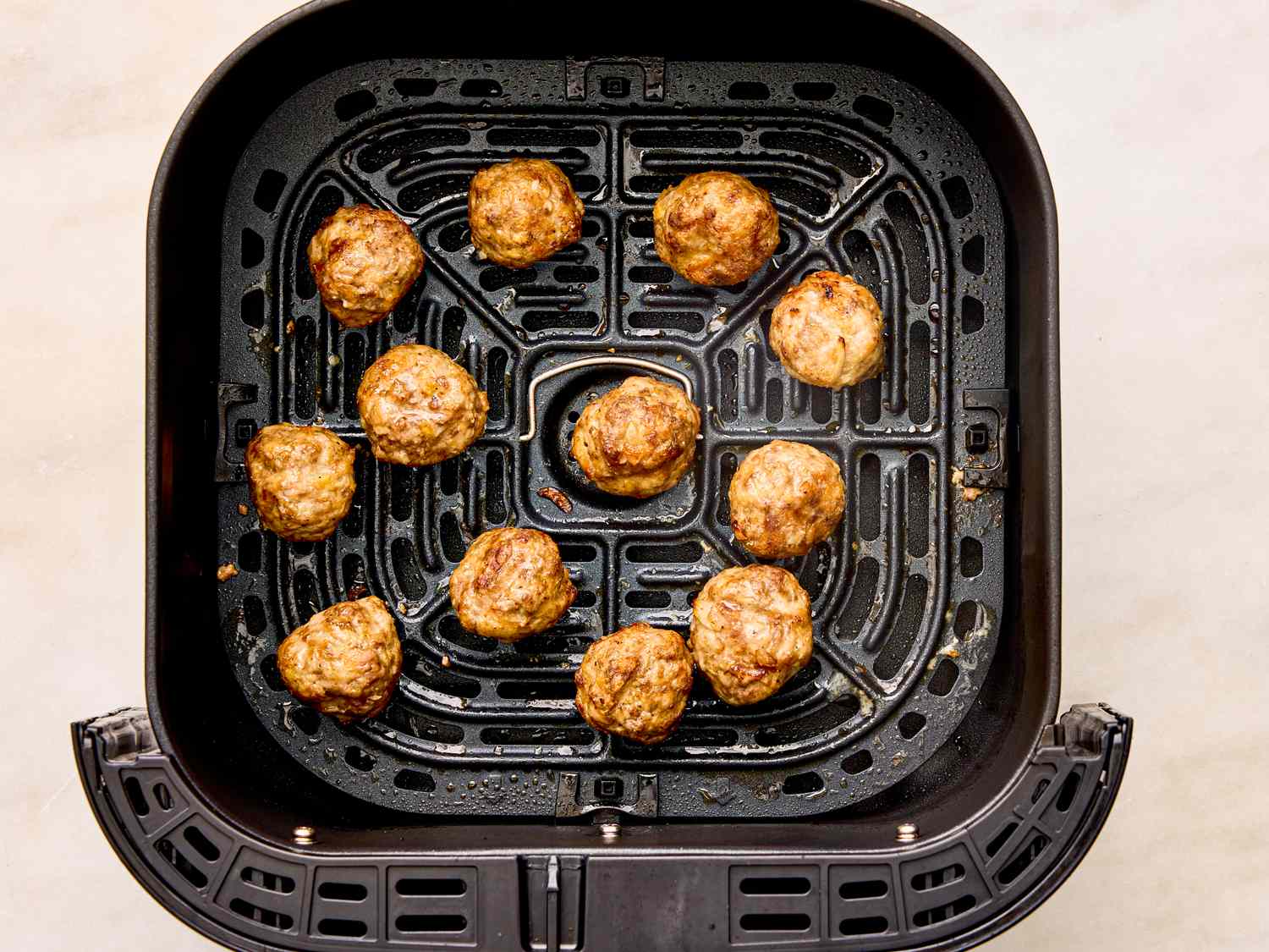 Cooked meatballs arranged in an air fryer basket