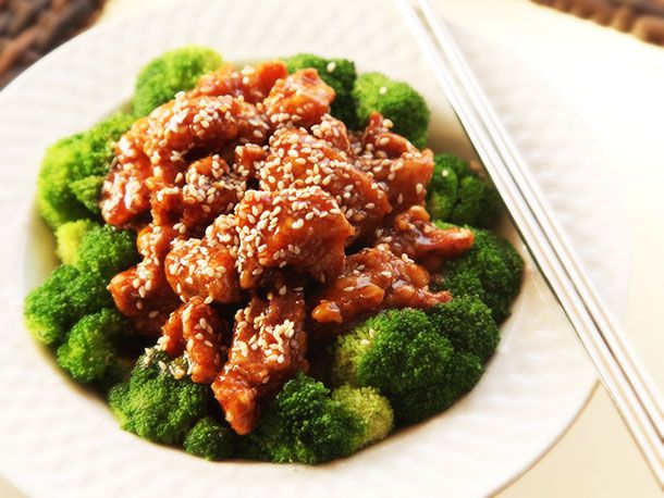 A plate of finished sesame chicken and broccoli, with chopsticks.