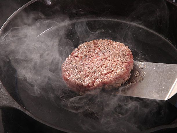 cooking burger patty on cast iron skillet