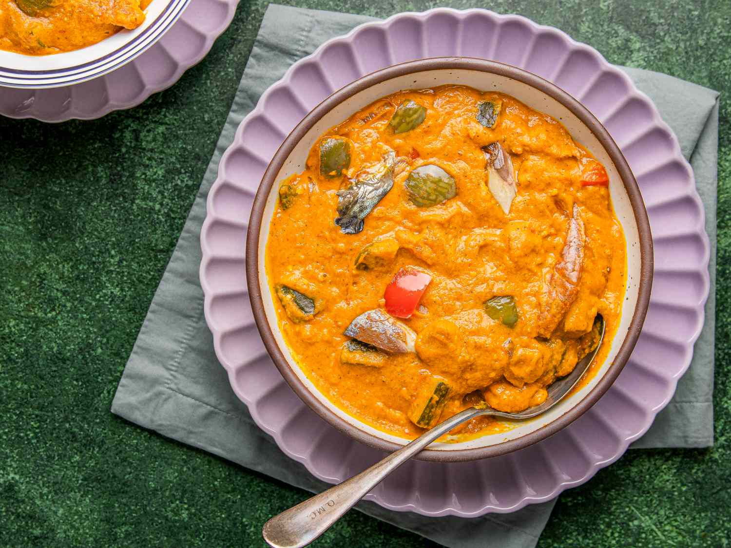 A bowl of Nigerian egg sauce served on a green placemat with a spoon