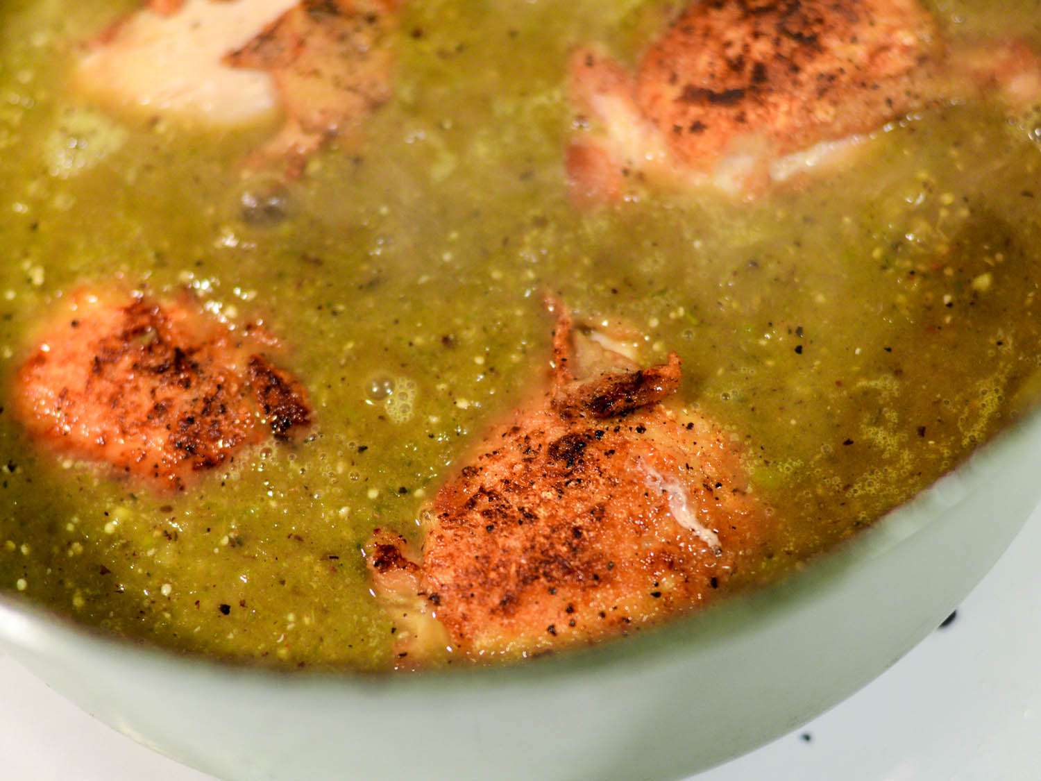 Brown chicken pieces nestled in green chile sauce