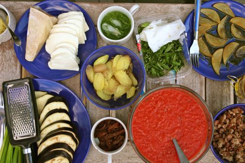 It's important to have all of your toppings assembled when making grilled pizza. Here are bowls of potatoes, greens, tomato sauce, eggplant, cheese, and more.