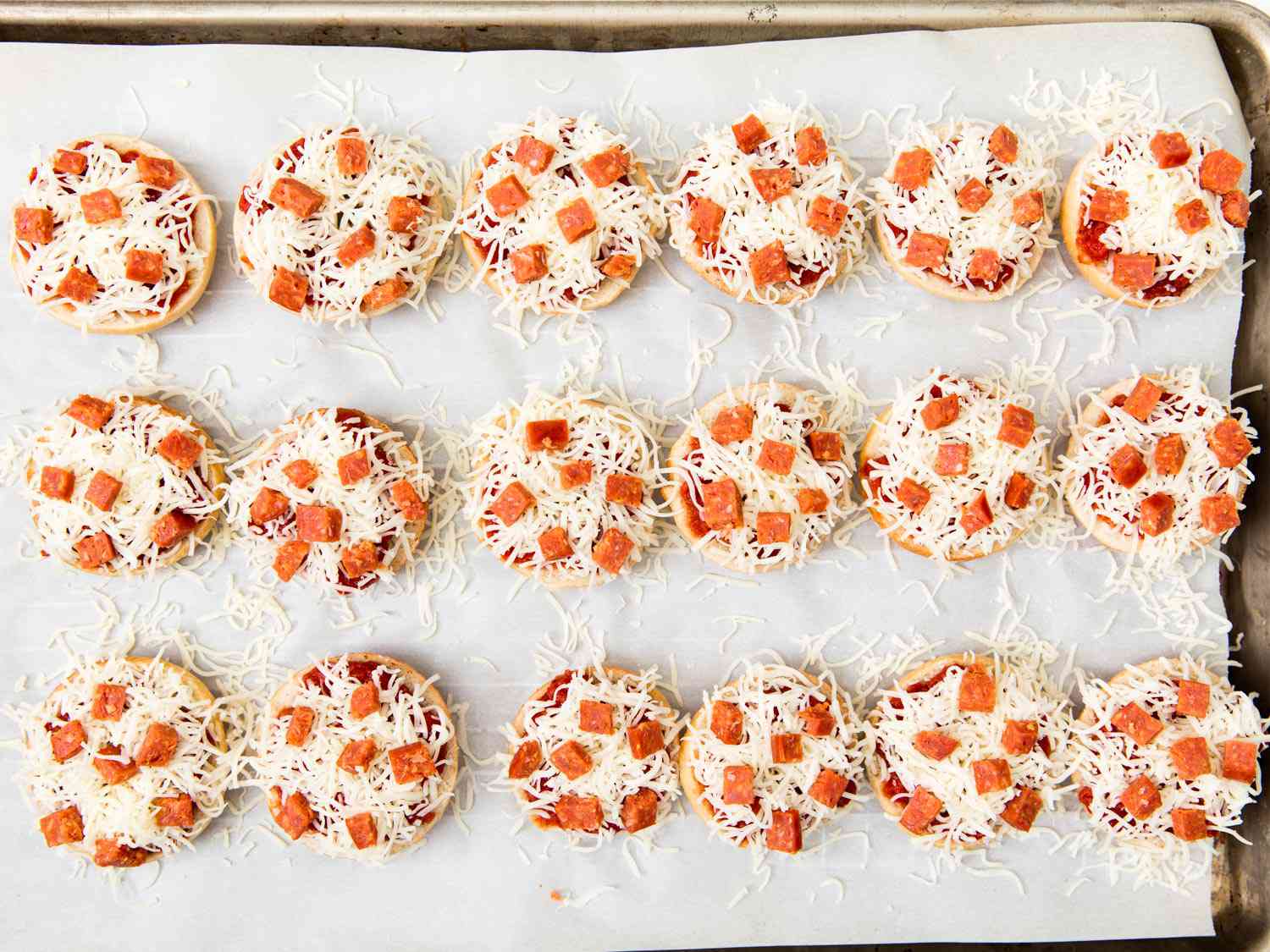 Split and topped mini bagels, ready to be transformed into bagel bites.