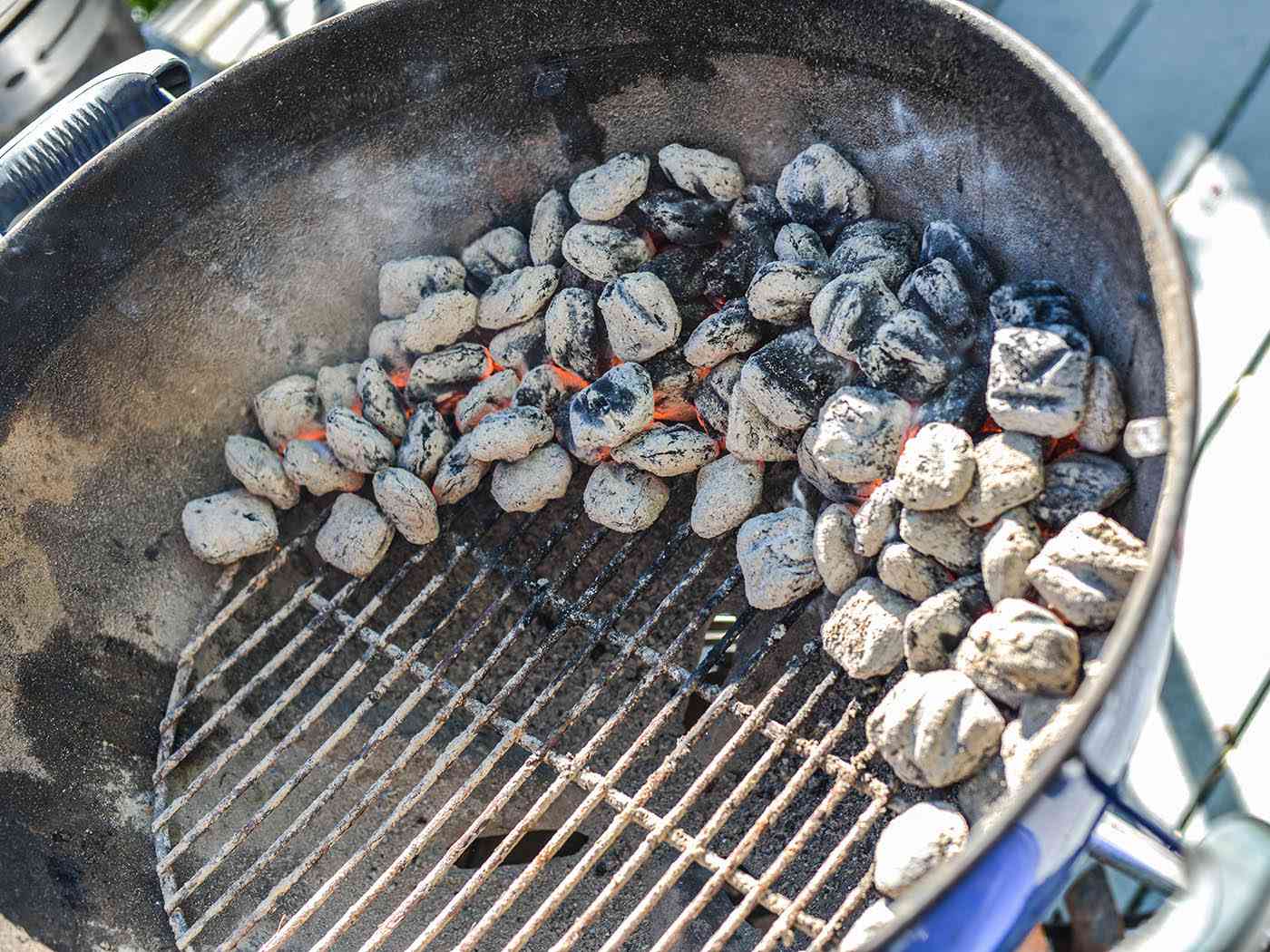 Placing the lit coals in a crescent shape to prepare for turkey grilling.