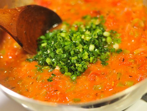 Adding parsley and thinly sliced green onion into Creole sauce. 