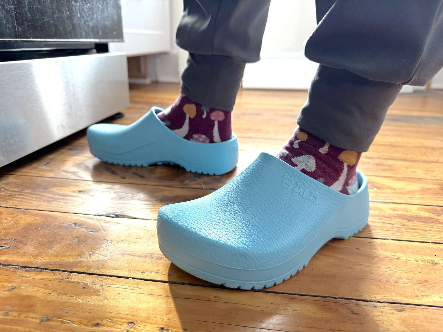A person wearing blue Birkenstock clogs.