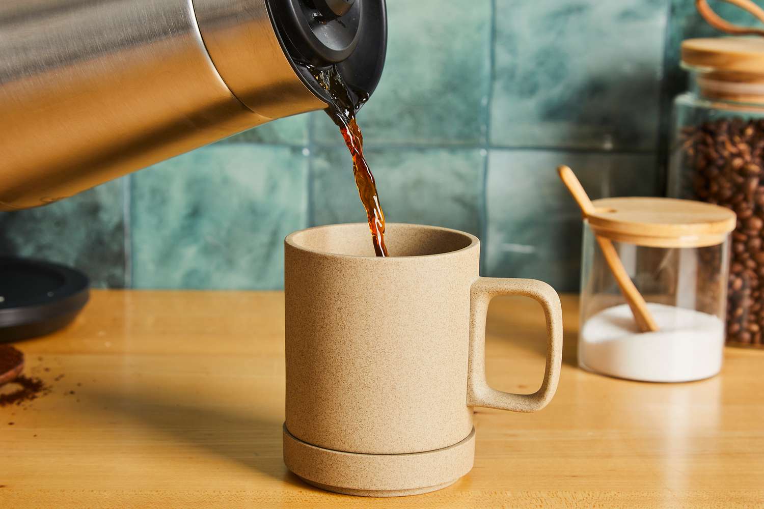 Pouring coffee into a tan ceramic mug.