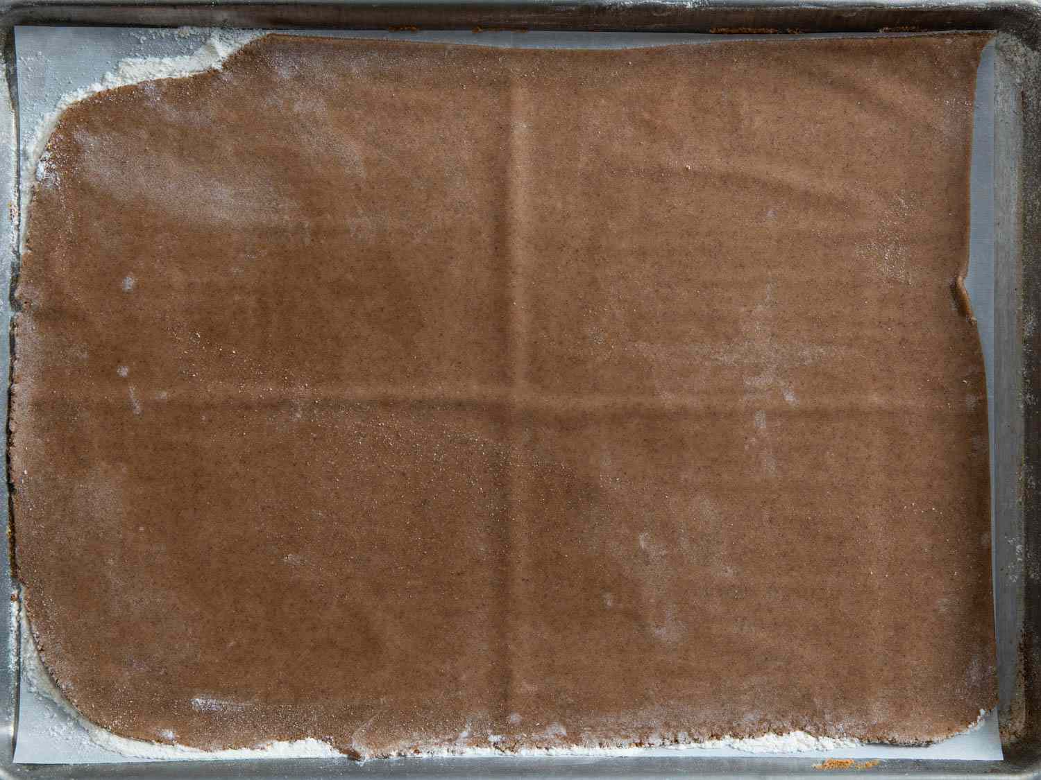 Construction house ginger bread rolled out in a parchment-lined baking sheet.