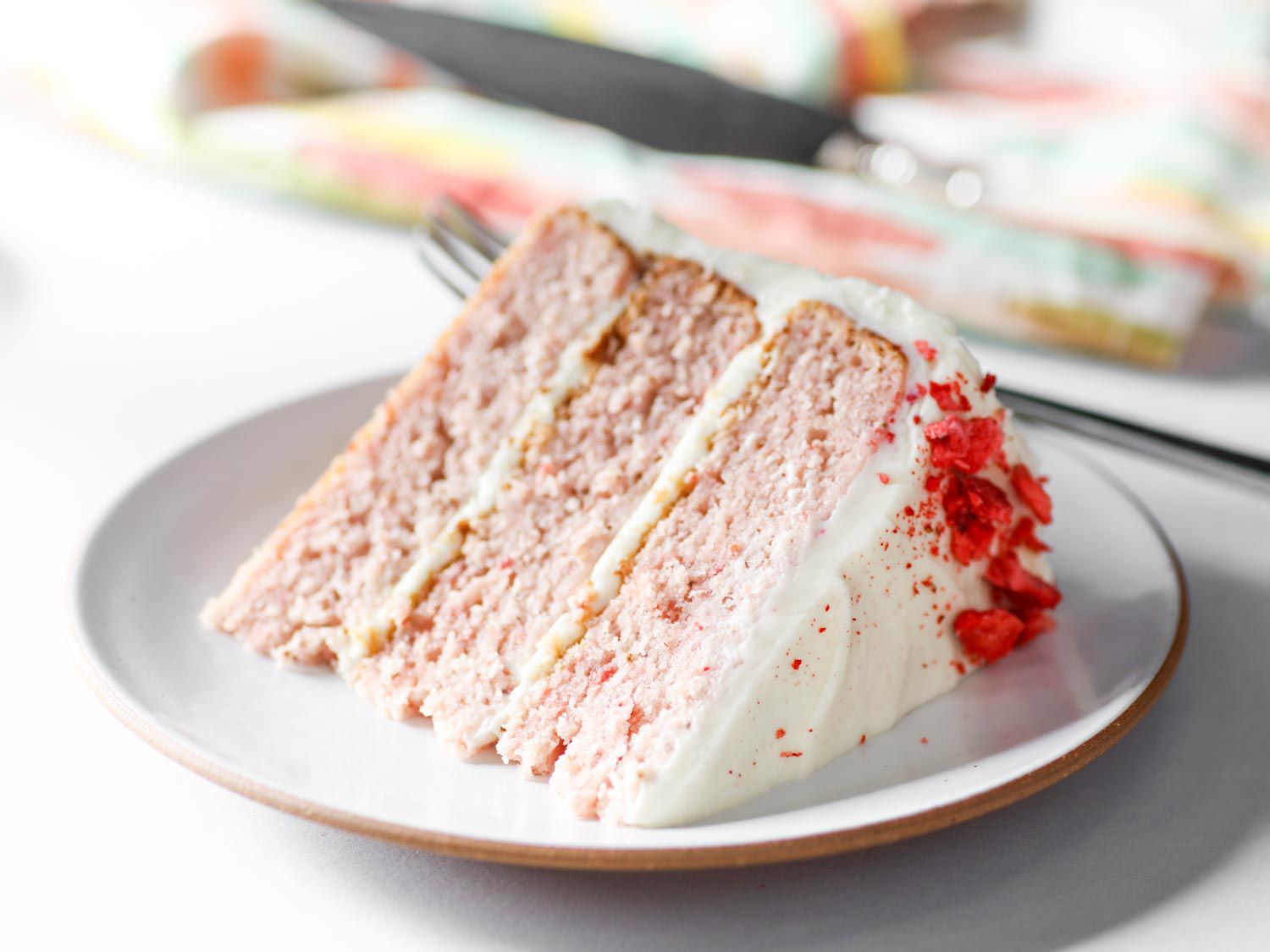 Wedge of strawberry layer cake on a white plate.
