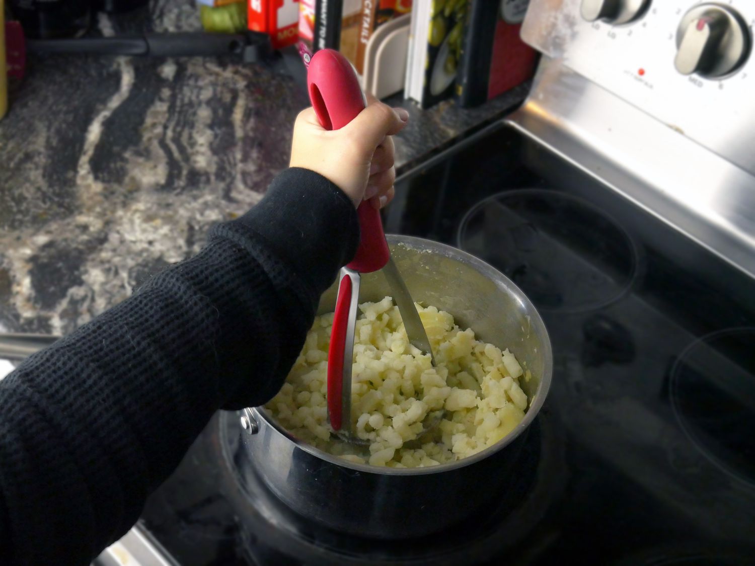 a person using the zyliss to mash potatoes