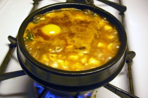 A pot of soondubu with a raw egg cracked into it