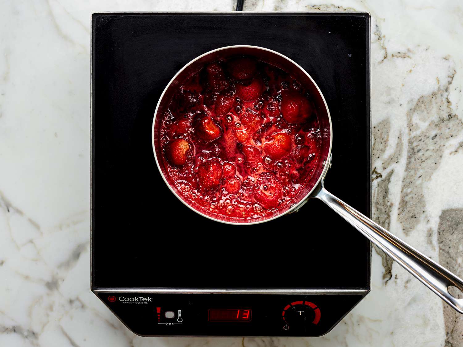 Berry sauce being cooked in a pot on a hot plate