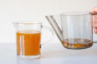 Two measuring cups one with liquid and the other being poured