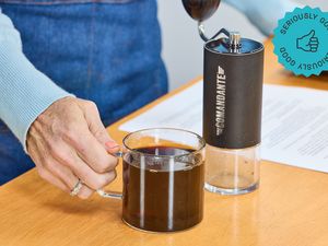 the comandante hand grinder with a cup of coffee next to it