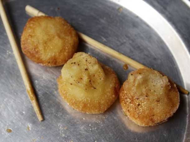Three banh cam resting in-between chopsticks on a metal plate