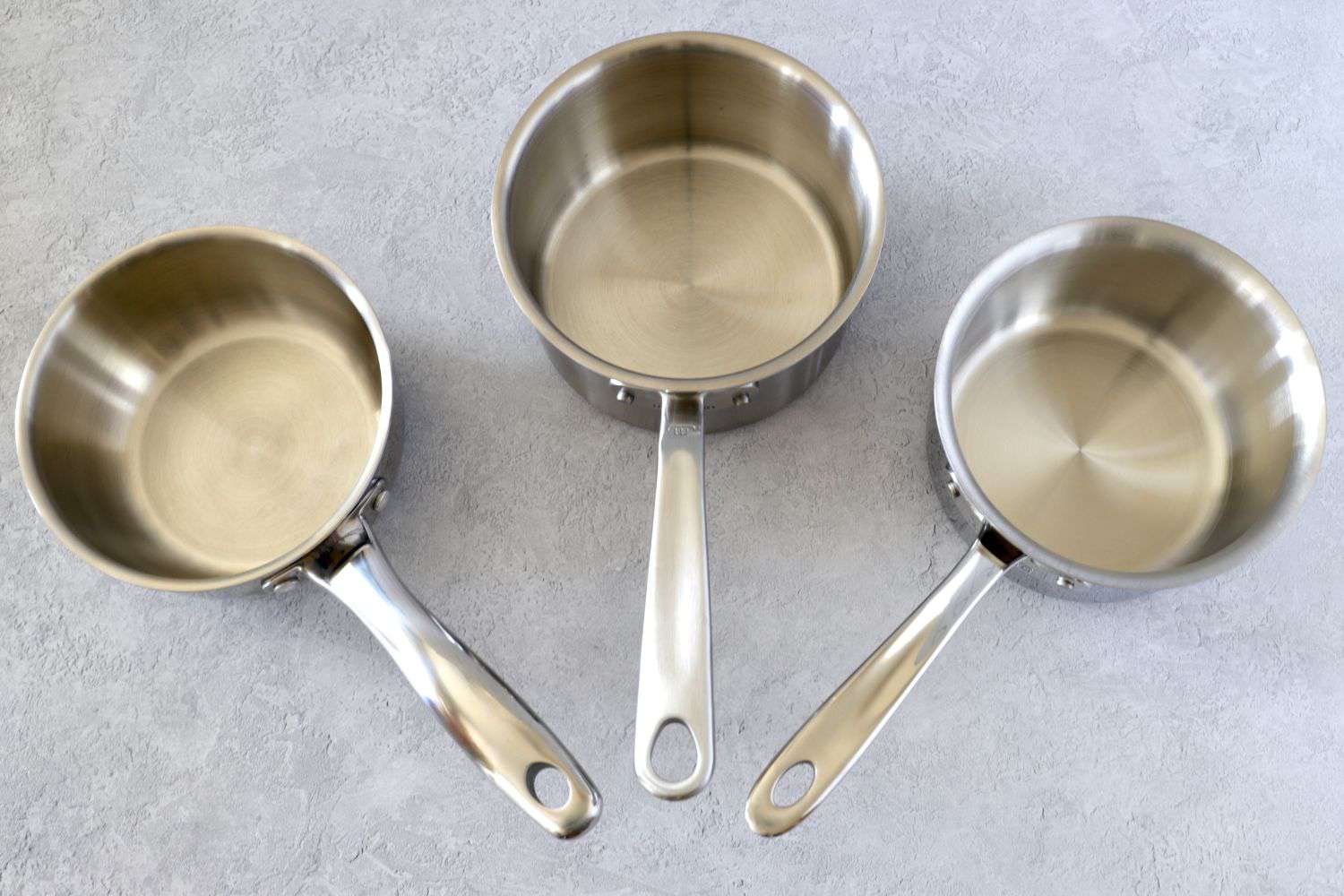 three saucepans on a grey surface