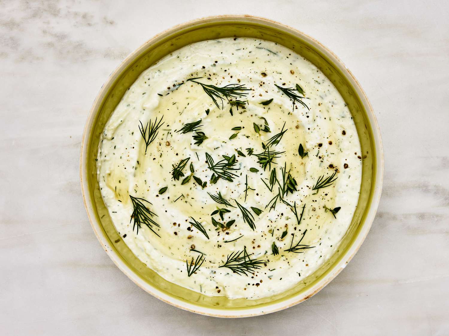 Bowl of feta dip with fresh dill, thyme and honey sprinkled on top 