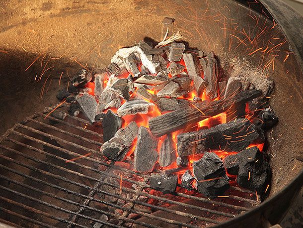 A chimney's worth of lit lump charcoal, piled high on one side of the kettle-style grill.