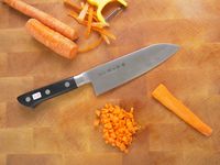 tojiro santoku on a cutting board with a cubed carrot