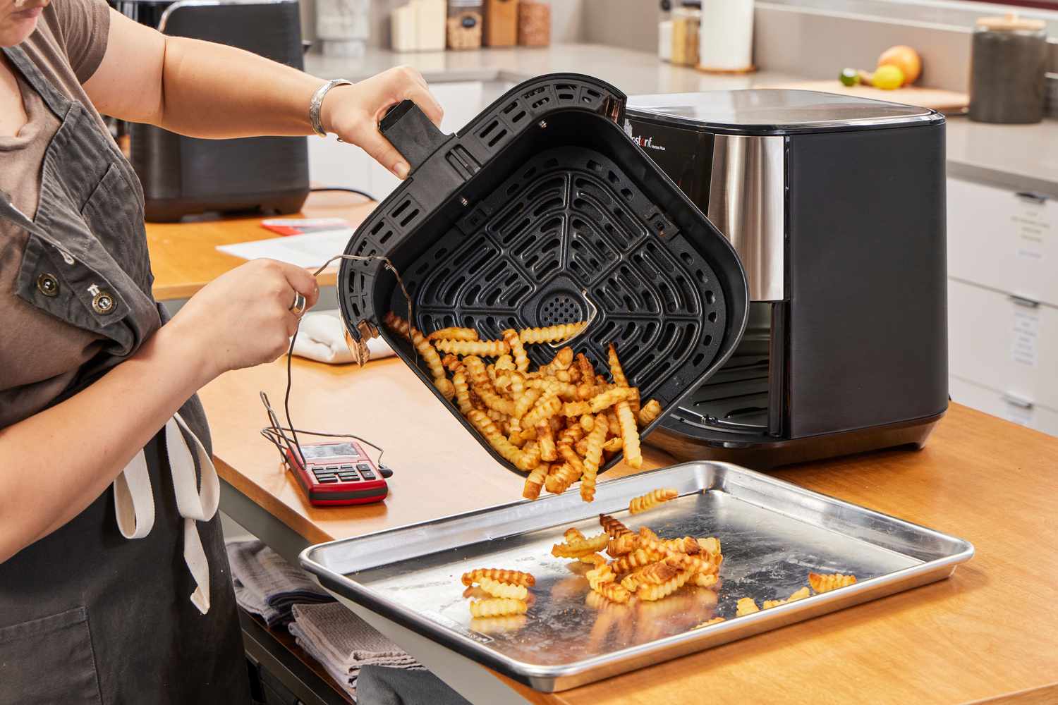 A person emptying fries from the Instant Vortex Plus 6QT XL Air Fryer onto a baking sheet