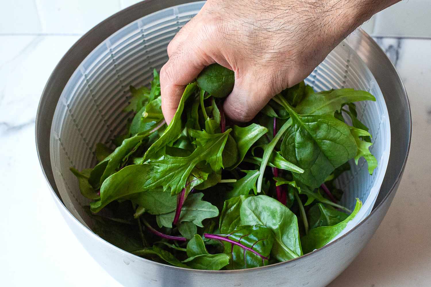 placing greens into the oxo steel salad spinner