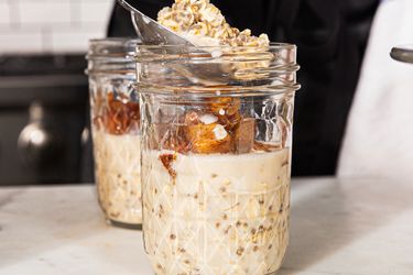 Preparing overnight oats in mason jars with oats milk and spiced apple topping