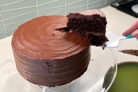 A closeup image of a chocolate cake on a glass cake stand