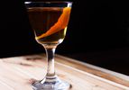 A three-ingredient cocktail called the Rob Roy garnished with a strip of orange peel.