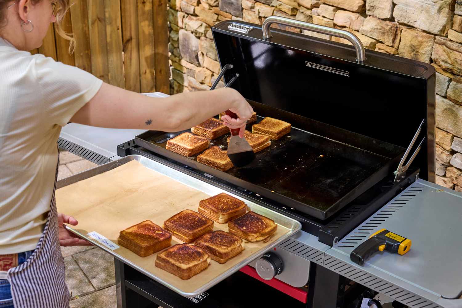 A person toasts sandwiches on the Weber Slate 28 inch Rust-Resistant 3 Burner Outdoor Griddle