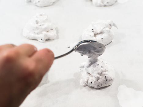 Scooping meringue onto a parchment-lined baking tray. 