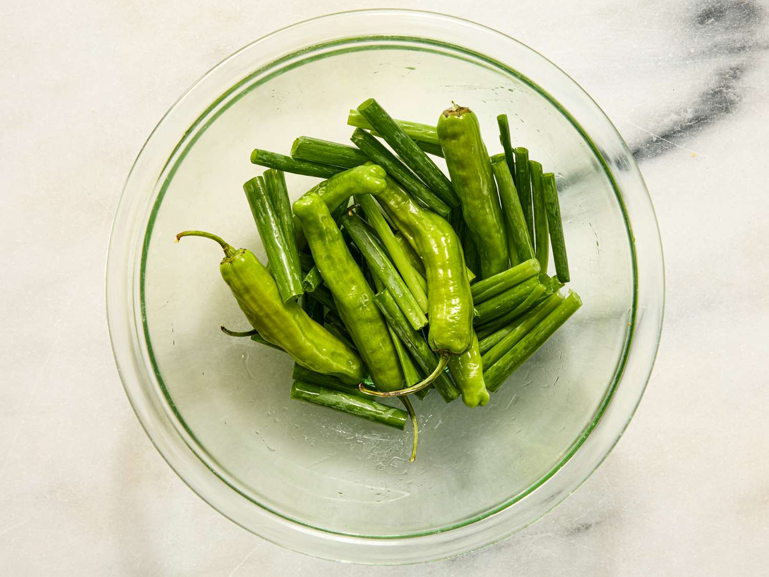 Fresh green peppers and scallions in a glass bowl prepared ingredients for a recipe