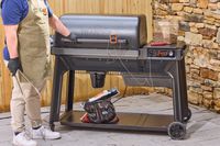 A person touches the lid handle on the Traeger Woodridge Pro Pellet Grill