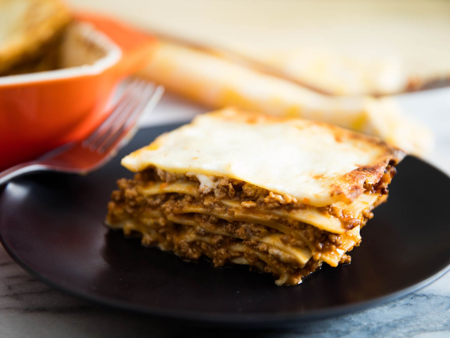A portion of lasagne alla bolognese served on a black plate.