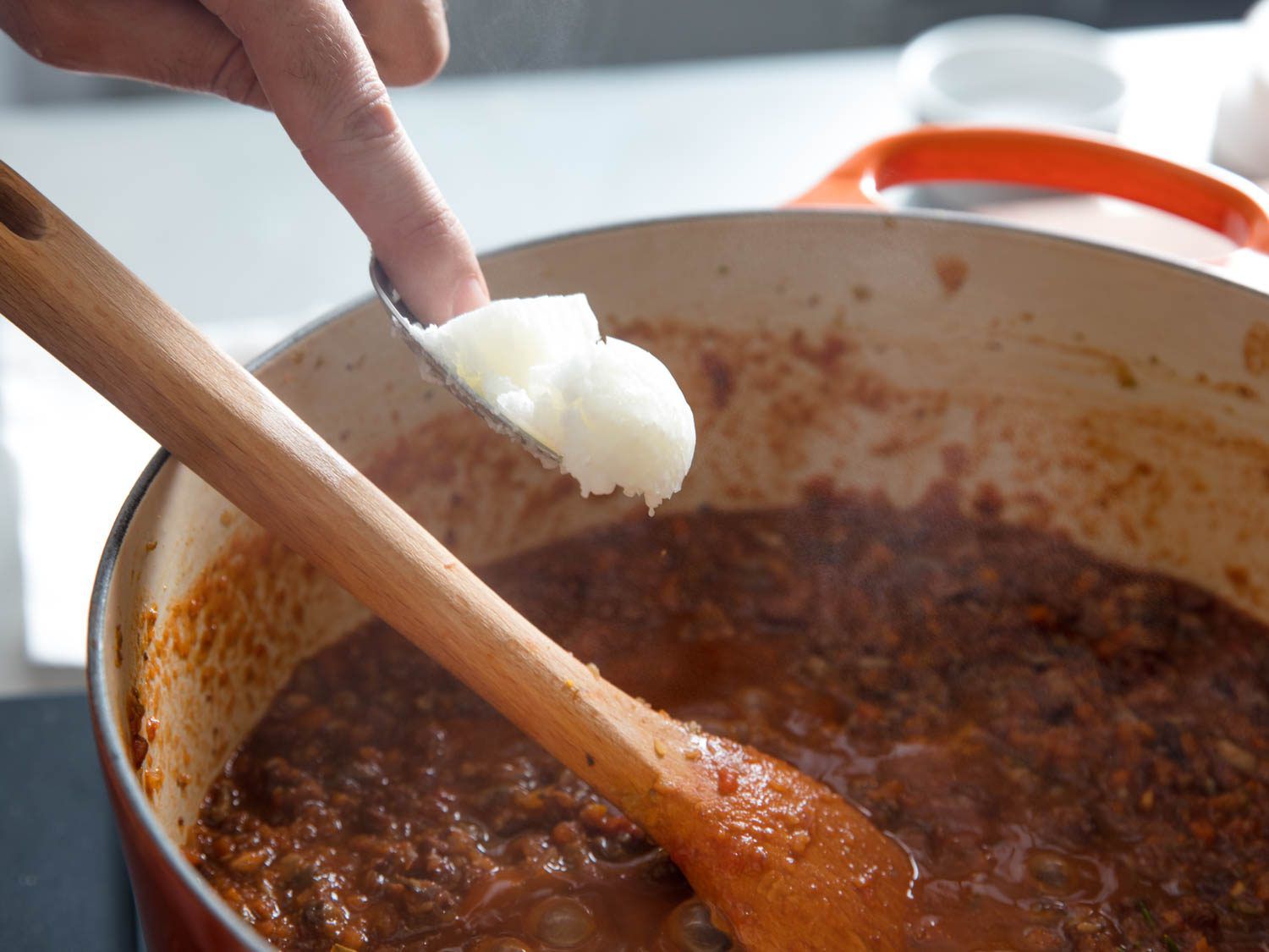 Adding coconut oil to vegan ragu for lasagna.