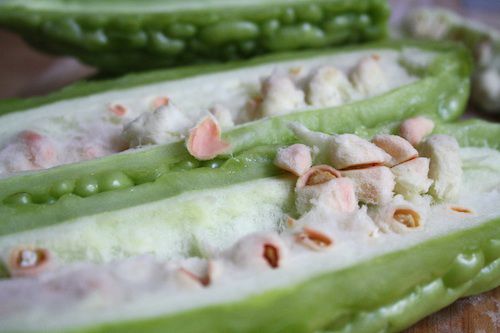 A bitter melon is sliced open lengthwise to reveal the seeds.