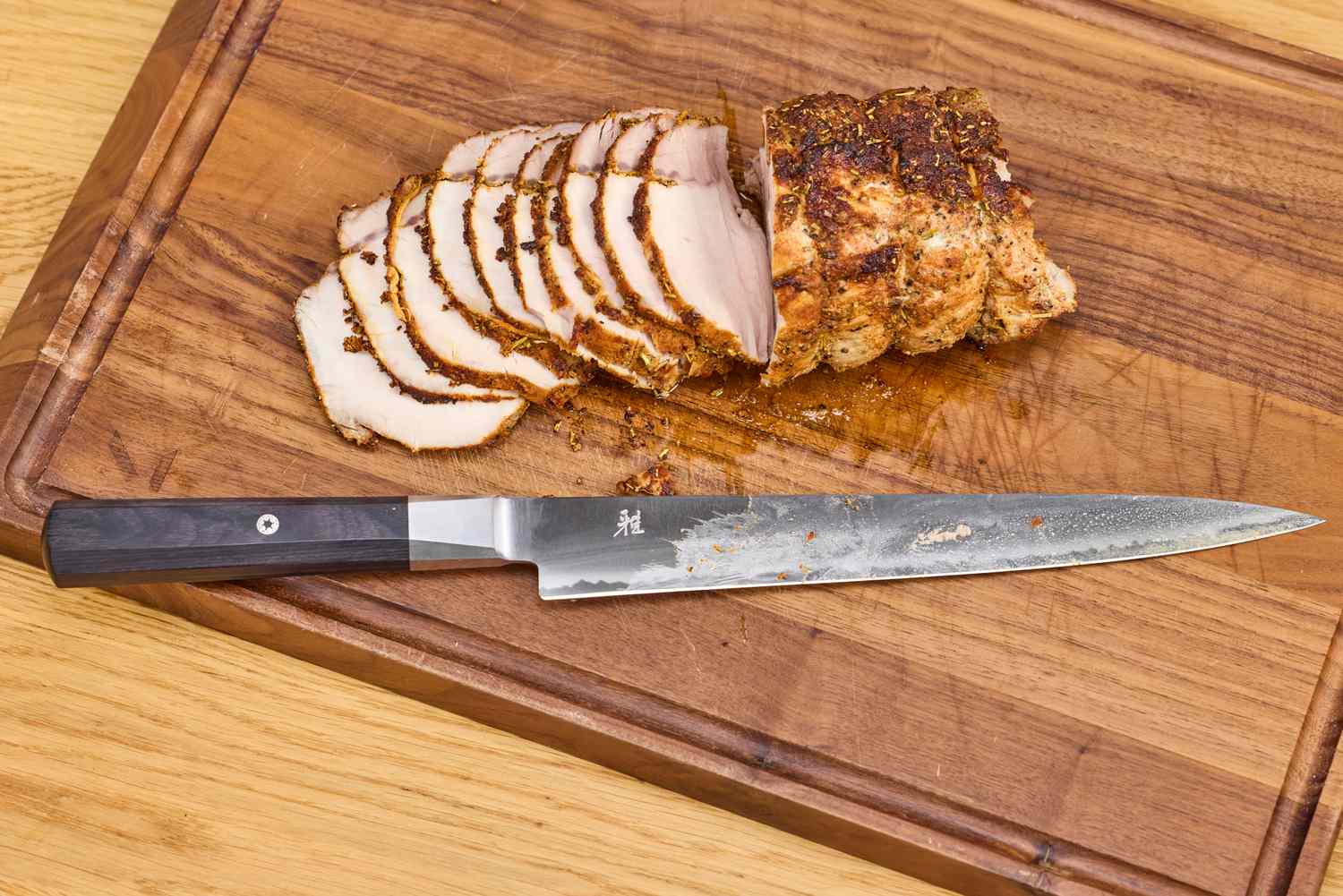 The Miyabi Koh 9.5 Inch Slicing Knife on a cutting board after slicing meat