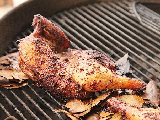 Smoked jerk-marinated half chicken on charcoal grill