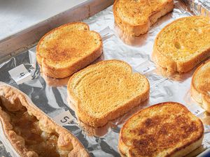 A variety of slices of garlic bread on a baking sheet numbered for a taste test