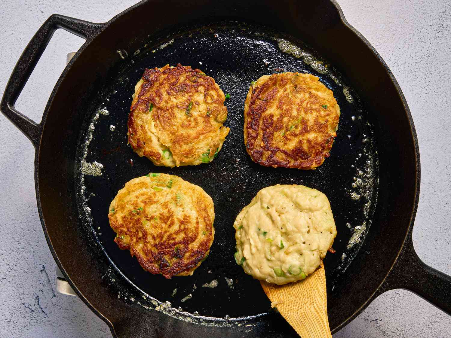 3 flipped boxty pancakes, while fourth is being flipped over with wooden spoon