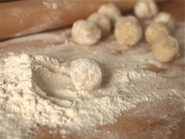 The dumpling dough rolled into balls on a heavily floured cutting board.