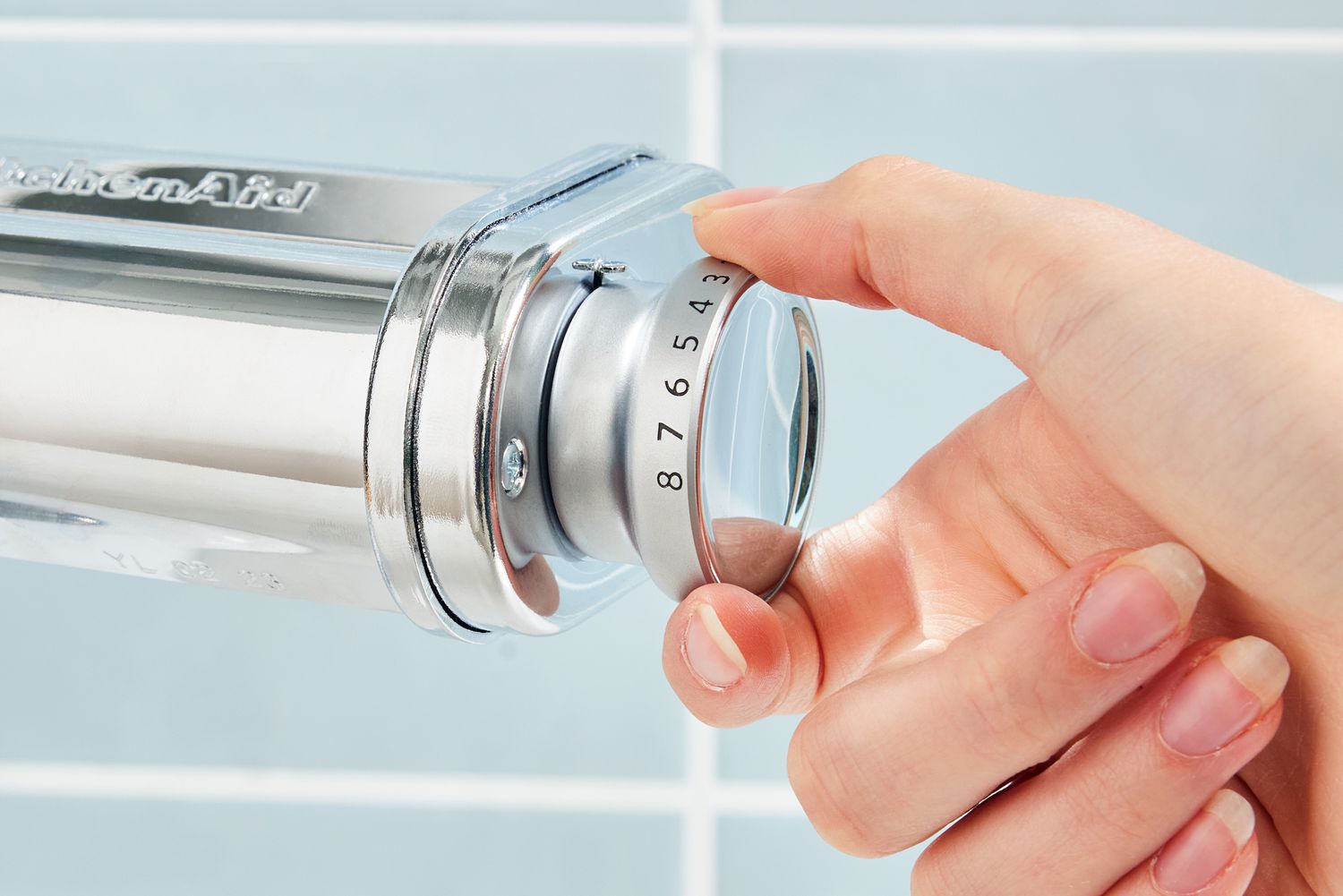 Closeup of hand adjusting knob on KitchenAid pasta roller attachment