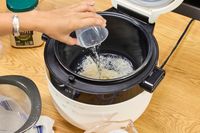 A person pours water into the Instant Pot 20 Cup Multigrain Cooker