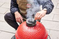 A person opens a smoke valve on the top of the Kamado Joe KJ13RH 13.5 inch Joe Jr. Charcoal Grill